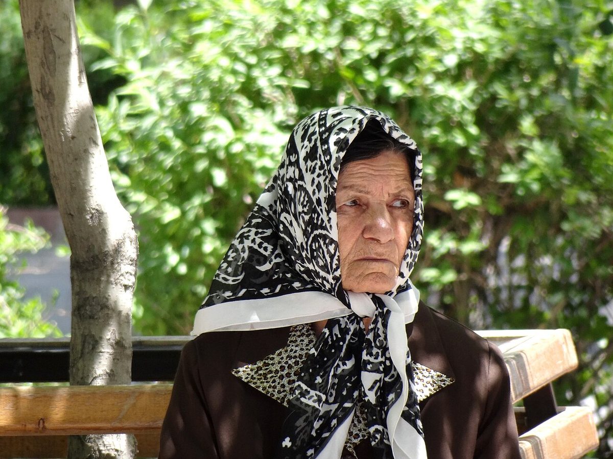 Elderly woman sitting in a park in Tabriz